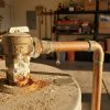 Leaking water heater T&P pressure relief valve, corroded copper pipe with rust and drip in garage.